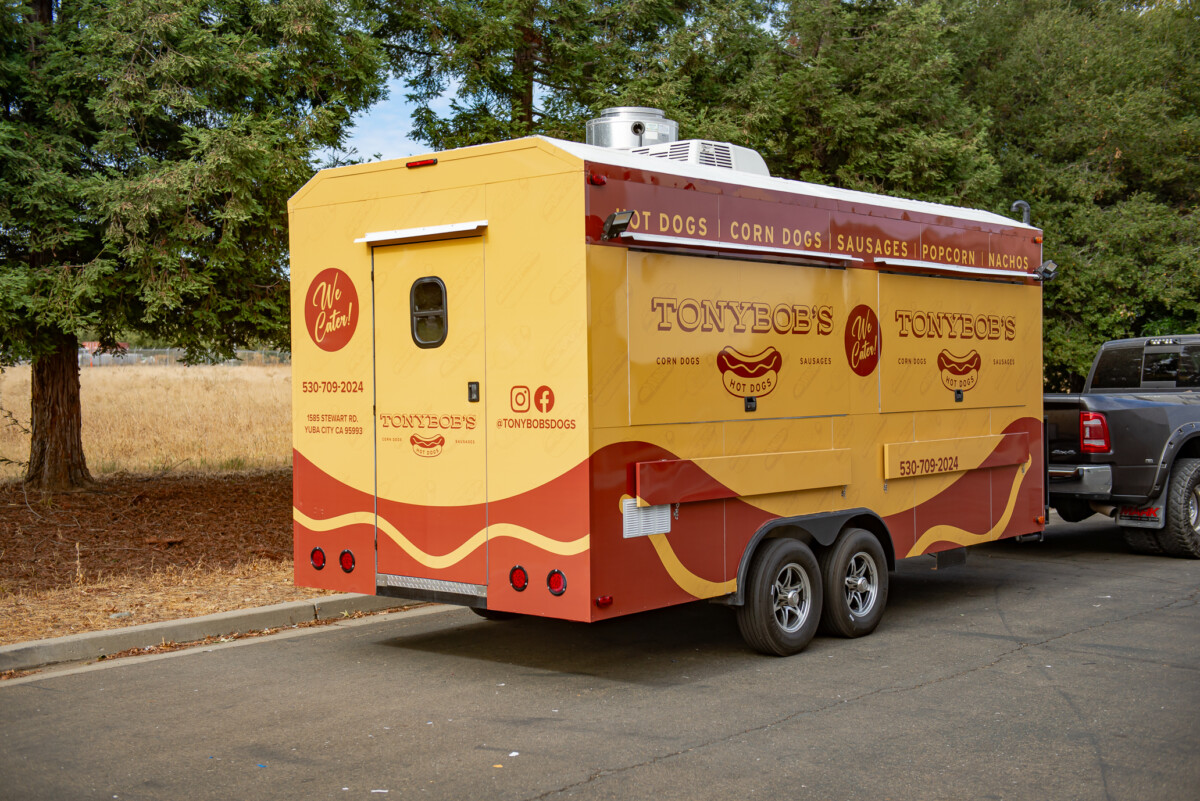 Full wrap food truck in mustard yellow and brown, showcasing hotdog-themed branding