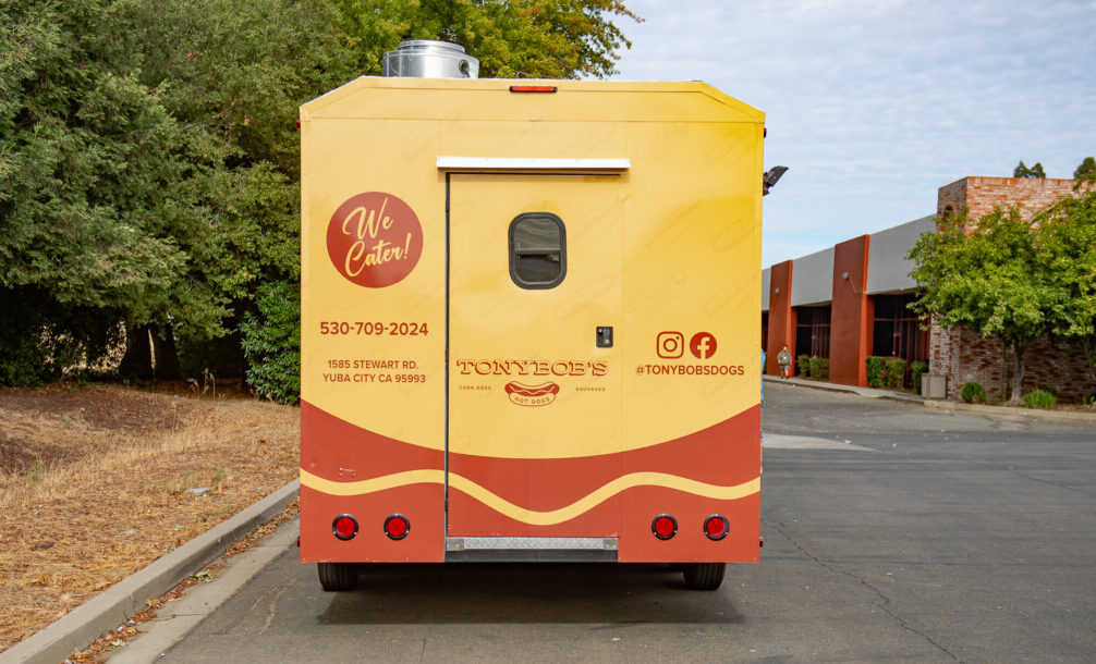 Tony Bob's Hotdogs truck fully wrapped with mustard yellow panels and brown accents.